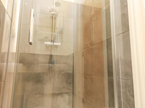 una doccia con una porta in vetro in un bagno di The Cottage a Pwllheli