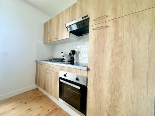 - une cuisine avec des placards en bois et une cuisinière dans l'établissement L'Epsilon, cosy et calme, à Limoges