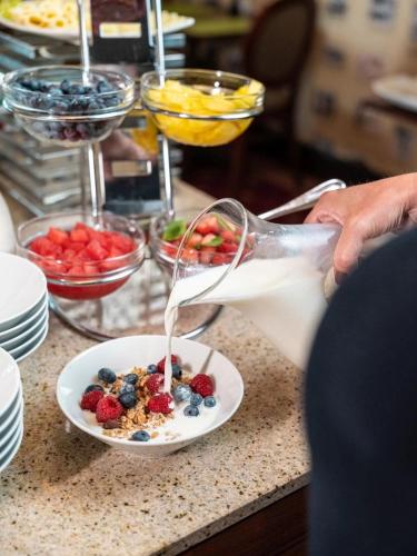 a person pouring milk into a plate of food at Willa z jacuzzi na polu golfowym Sierra Golf Homessimo Stars in Gowino