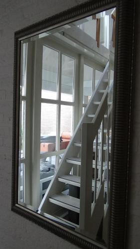 a mirror with a staircase in front of a window at Gardenhouse with private jacuzzi & private sauna in Teteringen