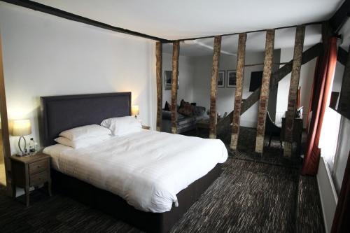 a bedroom with a large white bed and a staircase at The Saracens Head Hotel - The Coaching Inn Group in Great Dunmow