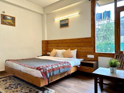a bedroom with a bed and a large window at Rockwood b&b in Manāli