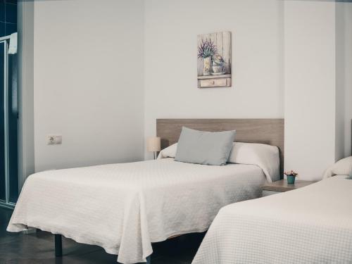 a bedroom with two beds with white sheets at Hostal Delia in Alora