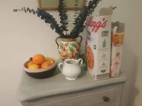 Ein Tisch mit einer Vase mit einer Pflanze und einer Schale mit Obst in der Unterkunft La Maison Haute in Nailhac