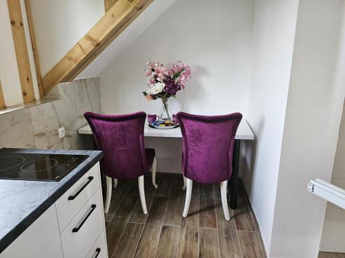 a table with purple chairs and a vase of flowers at Viktor Lux Apartmani 7 in Soko Banja