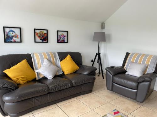 a black leather couch and a chair in a living room at Luxury town centre stay Ballycastle in Ballycastle