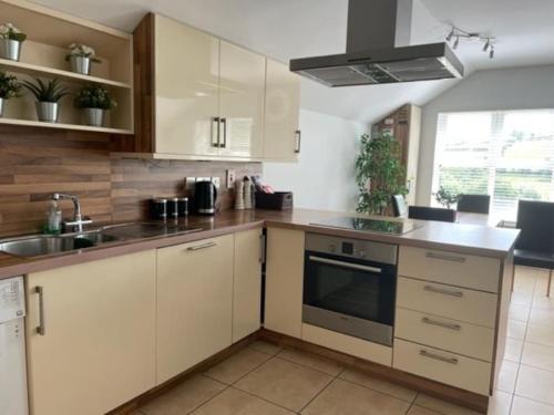 a kitchen with white cabinets and a sink at Luxury town centre stay Ballycastle in Ballycastle