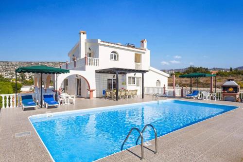 a villa with a swimming pool in front of a house at Villa Veronika by Villa Plus in Peyia
