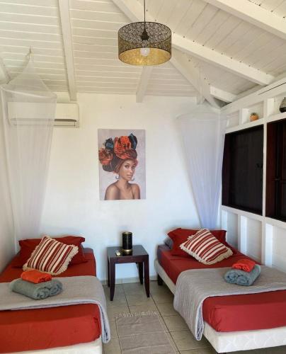a bedroom with two beds and a painting on the wall at Villa Palma avec vue mer et piscine privée location Domaine de la Pointe Batterie à Deshaies in Deshaies