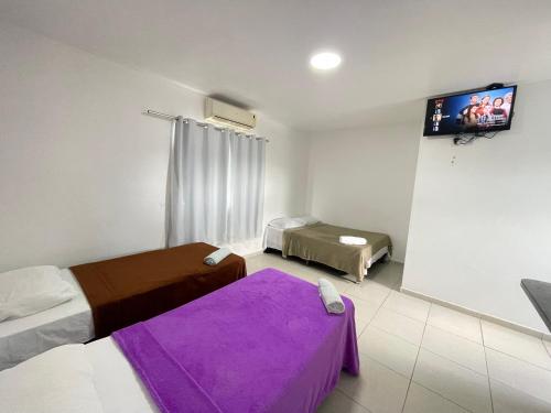 a bedroom with two beds and a tv on the wall at Pousada Anadia in Cajá