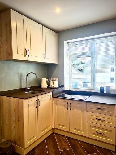 a kitchen with white cabinets and a sink and a window at Castle Mill Cottages in Wexford