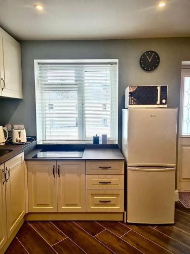 a kitchen with a refrigerator and a clock on the wall at Castle Mill Cottages in Wexford