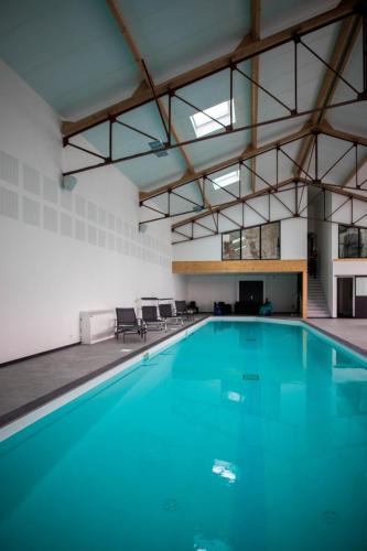 a swimming pool with blue water in a building at Villa moderne proche du Mans avec piscine intérieure in Dollon