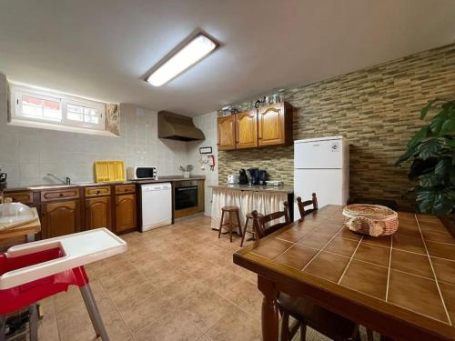 a kitchen with a wooden table and a kitchen with white appliances at Casa dos Cabencos in Terras de Bouro