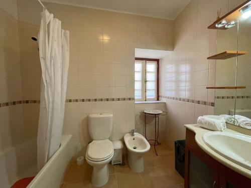 a bathroom with a toilet and a tub and a sink at Casa dos Cabencos in Terras de Bouro