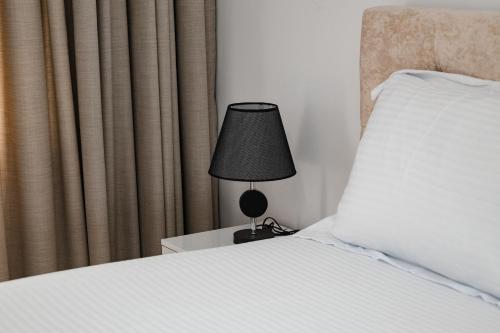 a lamp sitting on a night stand next to a bed at Riviera Hotel-City Center in Vlorë