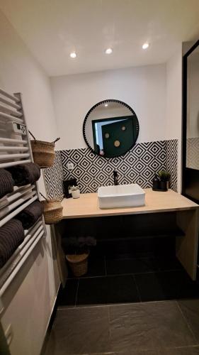 a bathroom with a sink and a mirror on the wall at Les Appartements du 104 in Saint-Jean-de-Monts