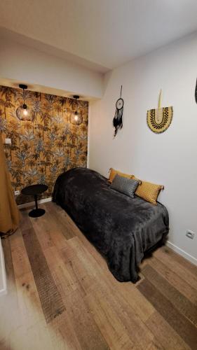 a bedroom with a large bed with a black blanket at Les Appartements du 104 in Saint-Jean-de-Monts