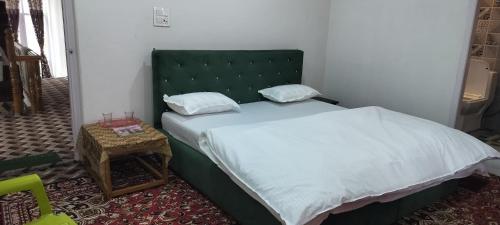 a bedroom with a large bed with a green headboard at Elizabeth paying guest house Tangmarg gulmarg in Gulmarg