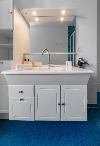 une salle de bain avec un lavabo et un grand miroir dans l'établissement Le Grenet - Appartement design en duplex, à Vichy