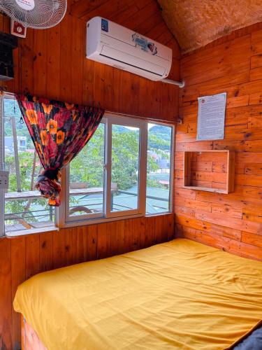 a bedroom with a bed in a wooden room with a window at Homestay Gấu Smile - Mộc Châu in Sơn La