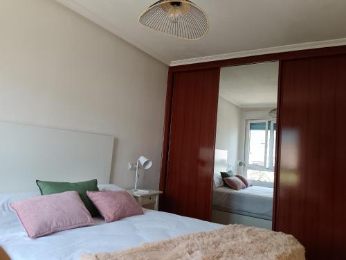 a bedroom with a bed with pink pillows and a mirror at Casa Ferino in Villaviciosa
