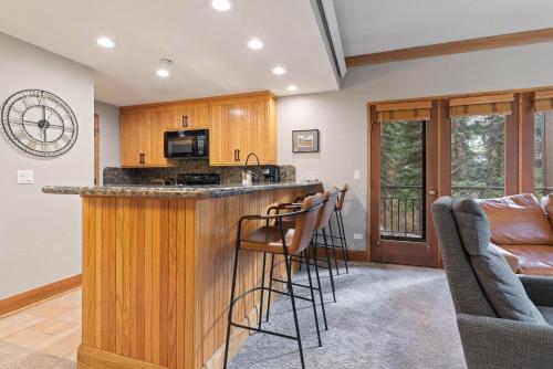 a kitchen with a bar with stools and a living room at The Charter at Beaver Creek C020 in Beaver Creek