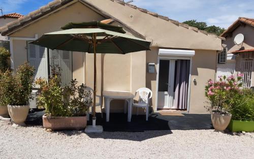 a table and chairs under an umbrella in front of a house at Appartement Meublé bord de mer FOS SUR MER in Fos-sur-Mer