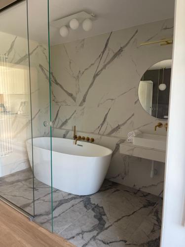 a bathroom with a white tub and a marble wall at Slow Home in Dziemiany