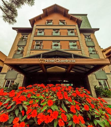 a building with red flowers in front of it at Hotel Querência in Gramado