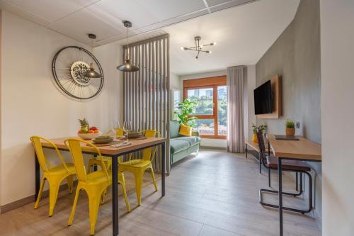 a dining room and living room with a table and yellow chairs at Spirit Apartamentos Atxuri in Bilbao