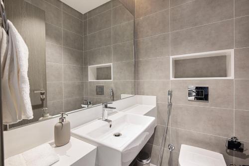 a white bathroom with a sink and a shower at Exclusive 1BR District 1 - Crystal Lagoon Access in Dubai