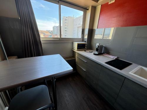 un bureau avec un bureau et une cuisine avec une fenêtre dans l'établissement Appartement terrasse au coeur de Valence 54, à Valence