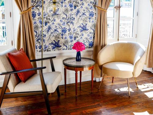 a living room with two chairs and a table with a vase of flowers at Maison d'hôtes - Stay and Cook in Annonay