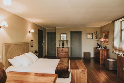 a bedroom with a large white bed and wooden floors at LOGIS HÔTEL-RESTAURANT - Le Moulin d'Artres in Artres