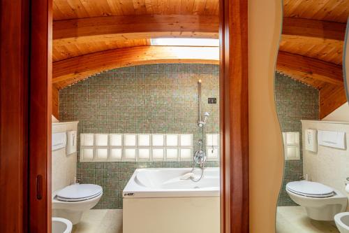 a bathroom with two toilets and a sink and a tub at Park Hotel in Lignano Sabbiadoro