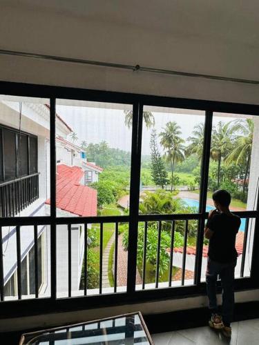 a person looking out of a large window at a house at Cim and Sands in Goa