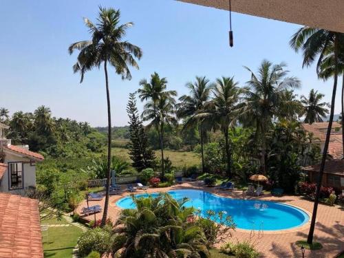 a view of a swimming pool with palm trees at Cim and Sands in Goa