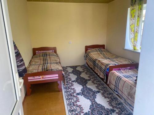 two beds in a small room with a rug at Restaurant & Hotel in Qonaqkǝnd