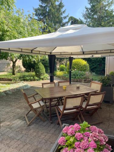 a wooden table and chairs under a white umbrella at The Originals Boutique, Hôtel Clos Sainte Marie, Nevers in Nevers