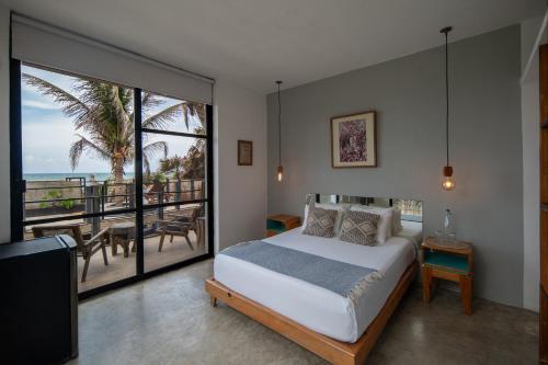 a bedroom with a bed and a view of the ocean at Tropicalito Villa on the Beach in Tulum