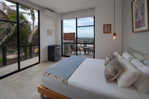 a bedroom with a large bed and a balcony at Tropicalito Villa on the Beach in Tulum