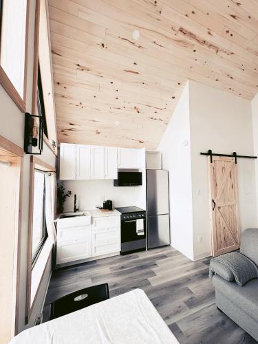 a kitchen with white cabinets and a wooden ceiling at À Bon Port in Perce