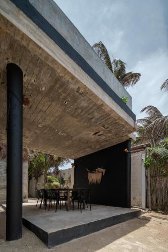 an outdoor patio with tables and chairs under awning at Tropicalito Villa on the Beach in Tulum