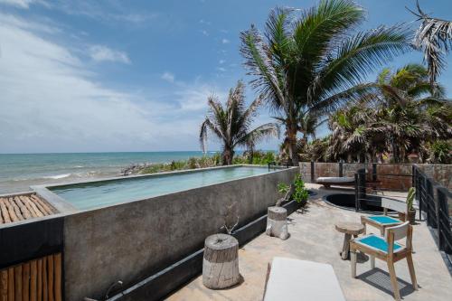 a swimming pool with the ocean in the background at Tropicalito Villa on the Beach in Tulum
