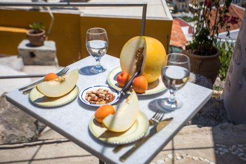 a table with plates of fruit and glasses of wine at kalosymi studio, Symi in Symi