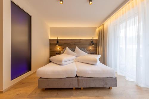a bedroom with a white bed with white pillows at Appartements zum Strossna in Mayrhofen