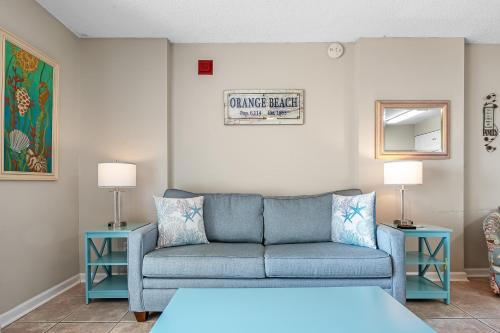 a living room with a blue couch and two tables at Tradewinds 307 in Orange Beach