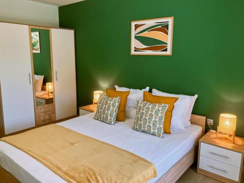 Dormitorio verde con cama grande con almohadas en ATEA Apartments, en Kavarna