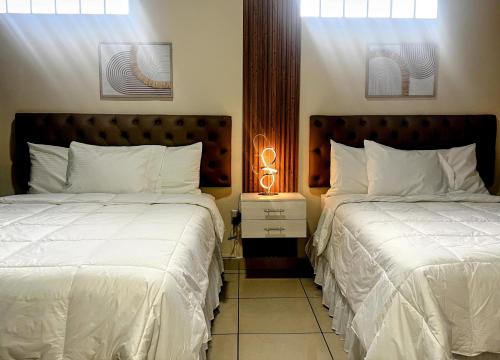 two beds in a hotel room with white sheets at GyV Executive in Tegucigalpa